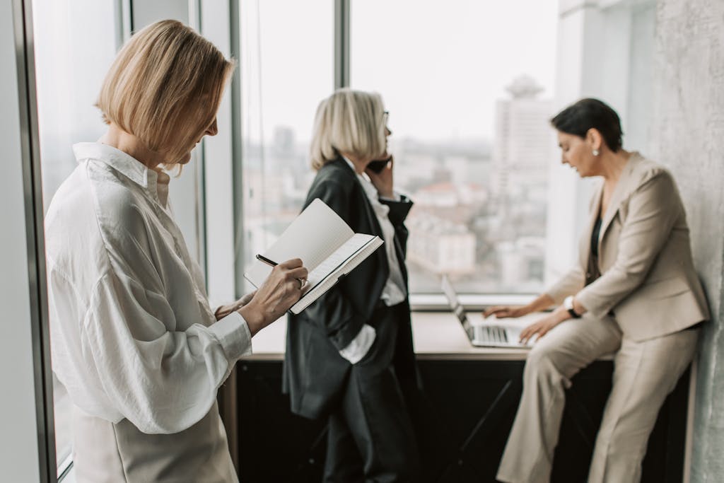 Three women collaborating in a modern office with city skyline background.